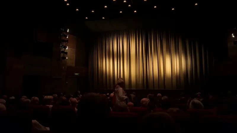 Lit stage curtain in a dark theatre